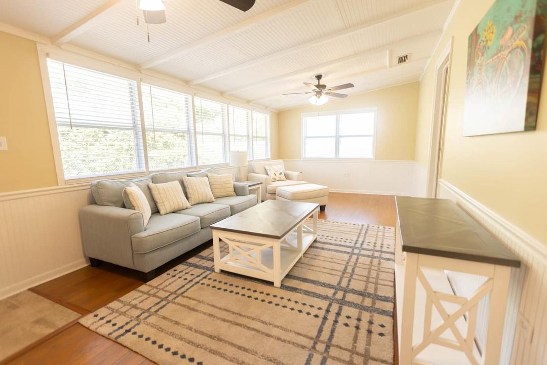 Den with a gray sofa, coffee table and woven rug