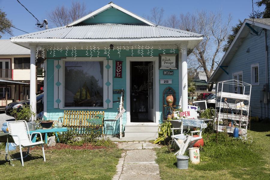 A small teal antiques shop with chairs and garden items out front on a Bay St. Louis street