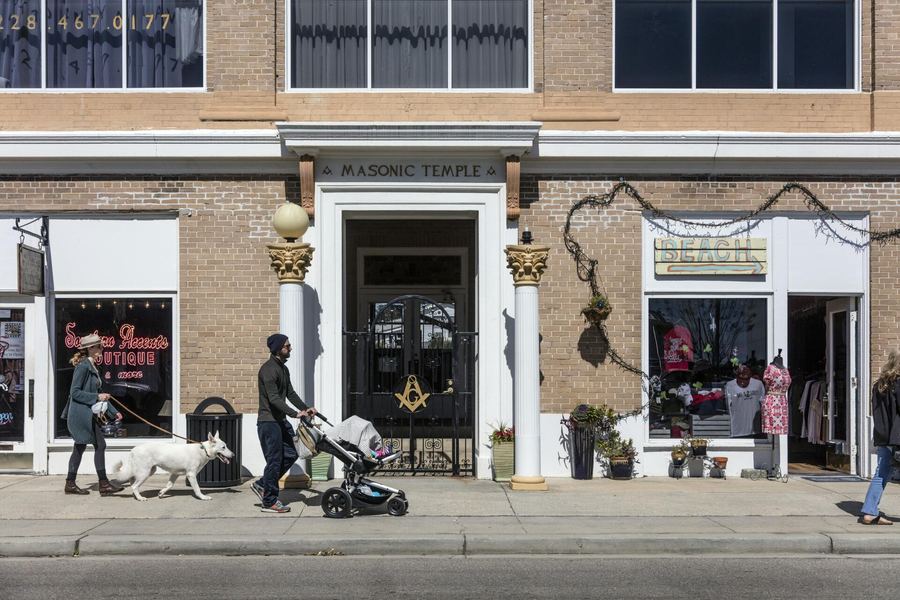 Brick storefronts on a Bay St. Louis street with people strolling