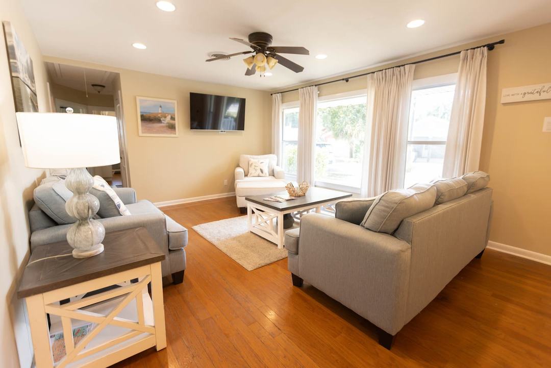 Living room with a gray couch, ceiling fan and wall-mounted TV